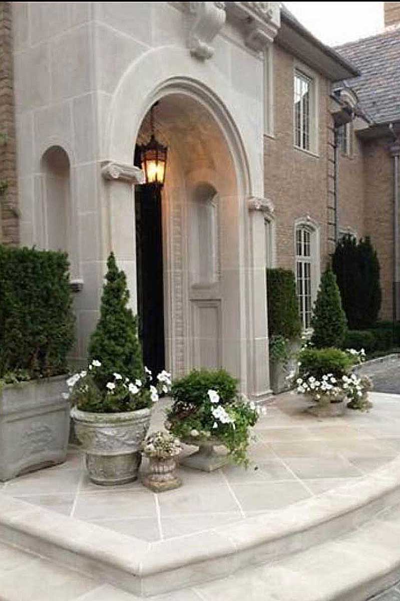 an entryway adorned with plants and topiaries